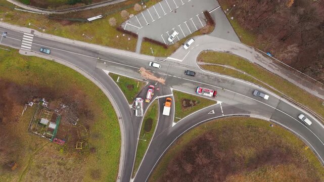 Firefighters clean an oil spill after a crash at a busy intersection, top down drone view