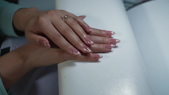 Demonstration of the completed nail extension result, client&rsquo;s hands rest neatly on the armrest, highlighting the elegant shape and glossy finish
