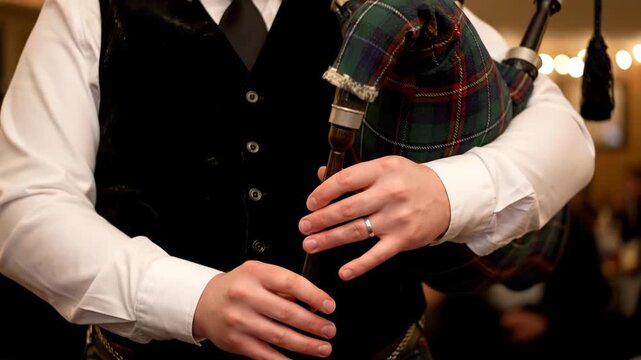 Close-up of a bagpiper playing the instrument at a formal event, with the bagpipe bag and pipes visible