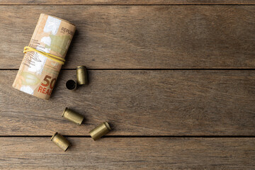 Used old ammunition casings with brazilian real bills with copy space