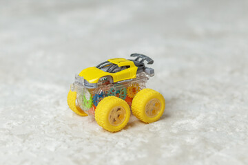 Obraz premium Yellow plastic toy car with visible gears on floor