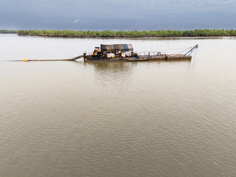 Aerial view of a dredger floating on the water with a dark forest in the background, Bukuma, Rivers, Nigeria.