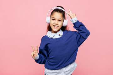 Little child kid girl 8-9 years old wears blue shirt have fun listen music in headphones show...