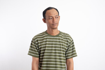 Fototapeta premium Asian man wearing green shirt with white stripes looking down, indicating confusion, or paying attention and searching for ideas.