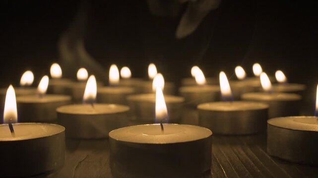 many burning memorial candles. Group of glowing candle lights in the dark, symbol of memory, mourning and memorial. Warm candle flame light for prayer