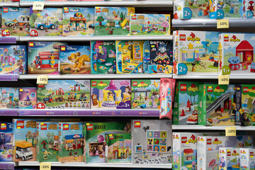 Obraz premium Lego products on a shelf in a shop. Various LEGO boxes, including City, Friends, Duplo and Disney themes, are neatly arranged on store shelves, ready for purchase. Minsk, Belarus - March 4, 2025