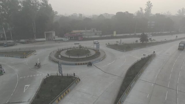 Aerial view of Banani Mor roundabout in Bogura during dense winter fog with light traffic, Bangladesh