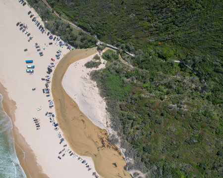 Aerial view of 75 Mile beach meeting the lush green forest, where Eli Creek flows into the ocean, K'Gari Fraser Island, Queensland, Australia.