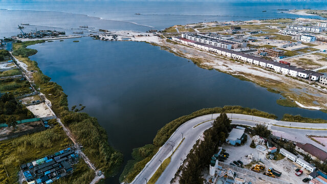 Aerial view of a tranquil lagoon mirroring the sky, bordered by lush greenery and the structured lines of Lekki Phase 1, Lekki, Lagos, Nigeria.