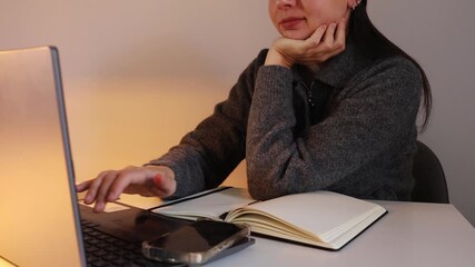 Young woman brunette working remotely from home with the laptop in the evening close up