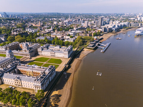 Aerial view of the majestic Old Royal Naval College and the serene River Thames meet under a vast sky, contrasting historic architecture with modern cityscapes, London, England, United Kingdom.