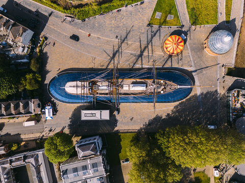 Aerial view of the Cutty Sark, a British clipper ship, contrasts against the bright blue dry dock and cobblestone plaza, London, England, United Kingdom.