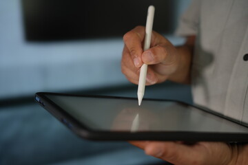 Obraz premium A focused person uses a white digital stylus on a sleek tablet screen modern technology, creative design, and digital productivity within a clean, minimalist and contemporary workspace.