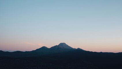 Serene mountain outline under a tranquil twilight sky with pastel pink and blue tones, suitable for landscape layouts