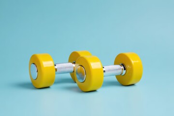 Obraz premium Centered yellow dumbbells on a blue background for fitness photography