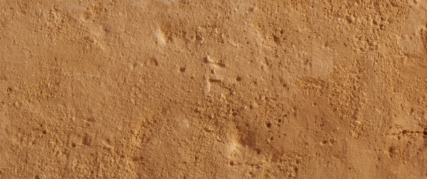 Old-fashioned house wall surface featuring brown beige sandy color and rough plaster finish