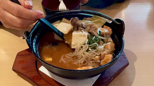 Salmon belly with spicy miso soup served in black bowl