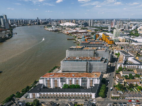 Aerial view of the River Thames snaking through a tapestry of modern buildings, leading to the iconic O2 Arena under a vast sky, Greenwich, London, United Kingdom.