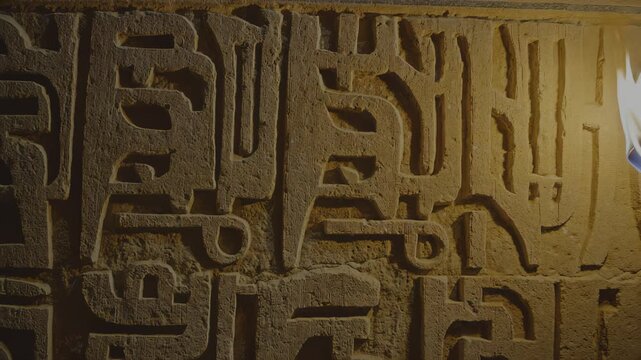 Ancient stone wall with intricate carvings illuminated by a flame, showcasing the detailed textures and patterns as the fire flickers and dances across the surface, hdr video with neutral color