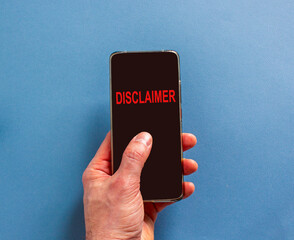 Disclaimer symbol. Concept word Disclaimer on beautiful cell phone's screen in businessman's hand. Beautiful blue background. Business disclaimer concept. Copy space.