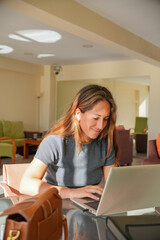 A woman is sitting at a table with a laptop in front of her