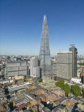 Aerial view of The Shard piercing the sky, juxtaposed against the tapestry of aged brick buildings below, creating a striking contrast of modern and traditional, London, United Kingdom.