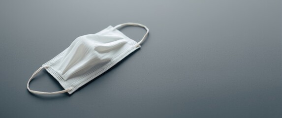 Hygienic white fabric mask on grey surface to prevent germs and particles