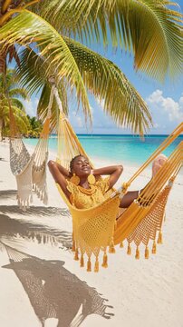 A woman is smiling and wearing yellow clothing. She is laying on a hammock by the ocean