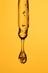 Cosmetic Pipette with Dripping Golden Oil or Serum Macro Shot