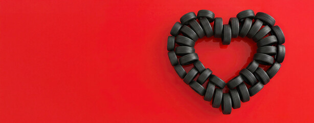 Banner with Heart shape created with black rubber tires on a vibrant red background, symbolizing love for automobiles and automotive passion, suitable for promotional or editorial use