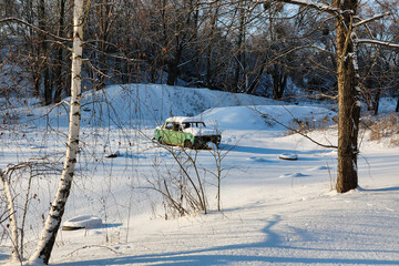 An old abandoned sports car is covered in snow