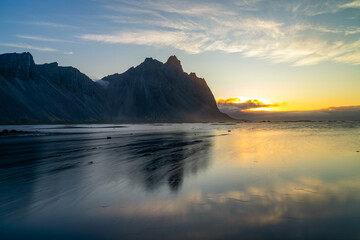 Obraz premium view of Stokksnes beach and the iconic Vestrahorn in warm morning light with reflections in the water