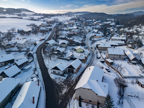Aerial view of snow-laden roofs and winding roads create a striking contrast against the winter landscape, Viglasska Huta-Kalinka, Banska Bystrica Region, Slovakia.