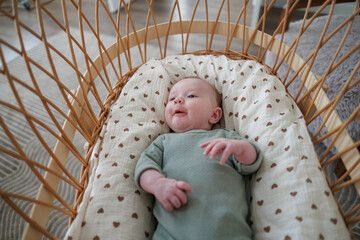 A portrait of a newborn baby in a crib. The baby is smiling and playing.