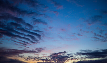 Fototapeta premium Dramatic Twilight Sky with Purple and Golden Clouds at Sunset,A breathtaking wide-angle shot of the evening sky during the golden hour. The image features a stunning gradient of deep blue and purple.