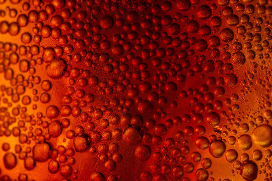 A close-up image of refreshing amber-colored cola soda bubbles against a golden light,Macro,An abstract macro shot of carbonated bubbles clinging to the side of a glass filled with a cold, Cola.