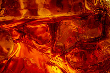 Macro Close-up of Ice Cubes in Cola Drink with Golden Light,A dramatic macro close-up of ice cubes submerged in a dark amber liquid, likely cola or whiskey. The image features intense golden.