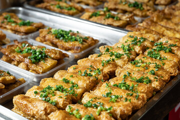 Macro close-up of Asian street food fried rolls topped with green onions, authentic local cuisine and travel concept