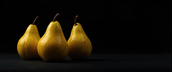 Three yellow pears against a black background in a detailed close-up, emphasizing fruit, garden, and health aspects