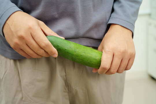 Male stands holding a cucumber, penis health.