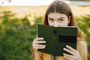 Young girl in a park looks with cunning eyes because of the book