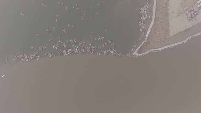 Aerial drone view of the Sangam during Magh Mela in Prayagraj. Boats move across the meeting point of the Ganga, Yamuna, and mythical Saraswati, with pilgrims gathering along the riverbanks. The scene