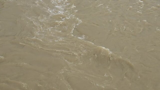 Close-up of turbulent, murky brown river water swirling rapidly during the rainy season.