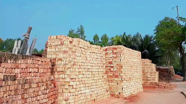 Large stacks of red clay bricks arranged in rows at a construction site or brickyard.