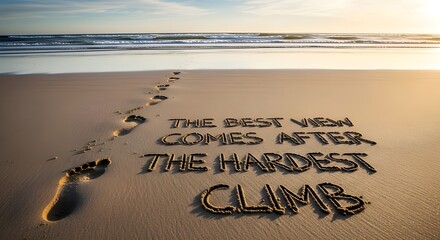 Footprints leading towards an inspirational message written in sand about achieving success after facing challenging difficult times on the beach at sunset