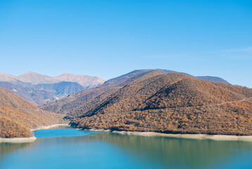 Obraz premium Turquoise lake mirrors mountains beneath clear sky