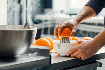 manual juicer in a stainless steel bowl. Orange juice.