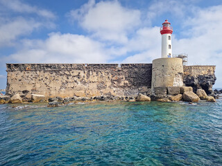 The lighthouse of Fort de Brescou, an historic sea fortress located on a small, volcanic island off Cap d'Agde, France. The ancient stone ramparts rise from the turquoise Mediterranean waters