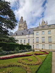 The Tours Cathedral with view from its formal gardens. The foreground features manicured hedges and vibrant flowerbeds in swirling patterns
