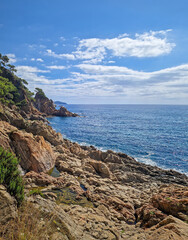 Sunny coastal view with sea waves gently crashing against the rocky shoreline. Beautiful turquoise water coastline of Cala sant Francesc Beach in Blanes (Costa Brava), Spain